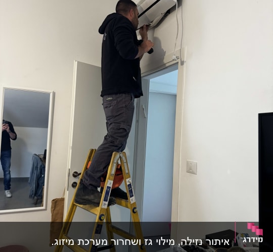 אדם על סולם מתקין מזגן על קיר לבן